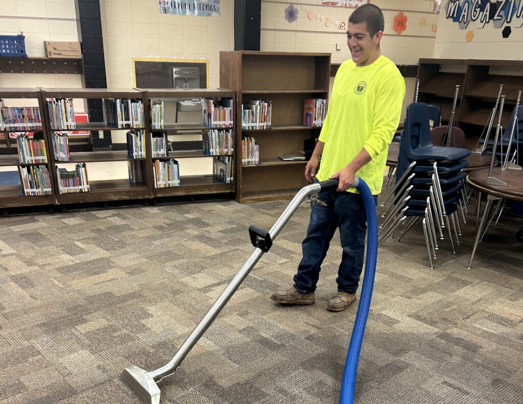 Recoveron technician extracting water from carpet in a school library