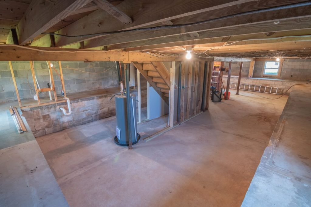 Unfinished basement with open wall framing and exposed pipes